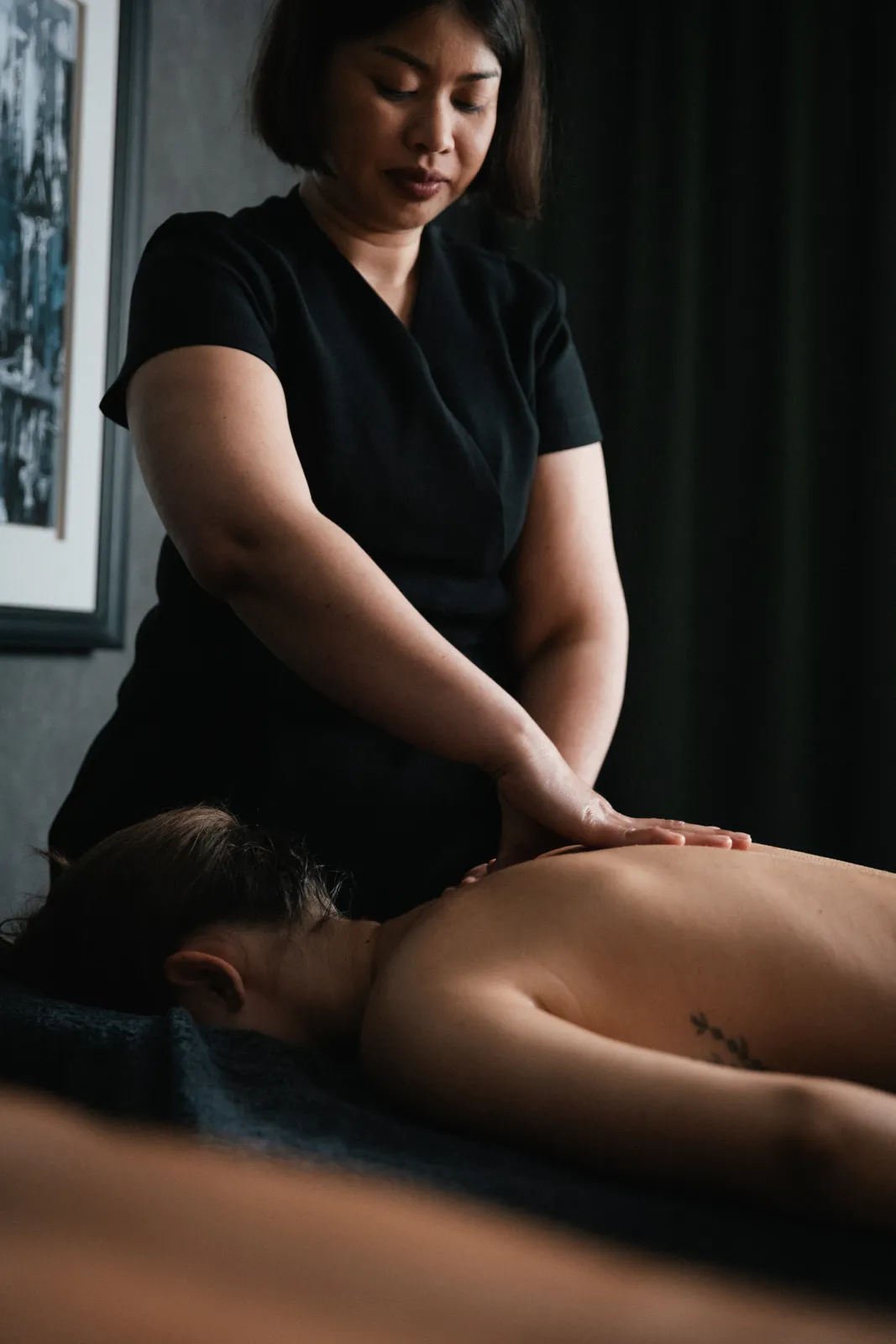 A therapist giving a back massage in a dim treatment room