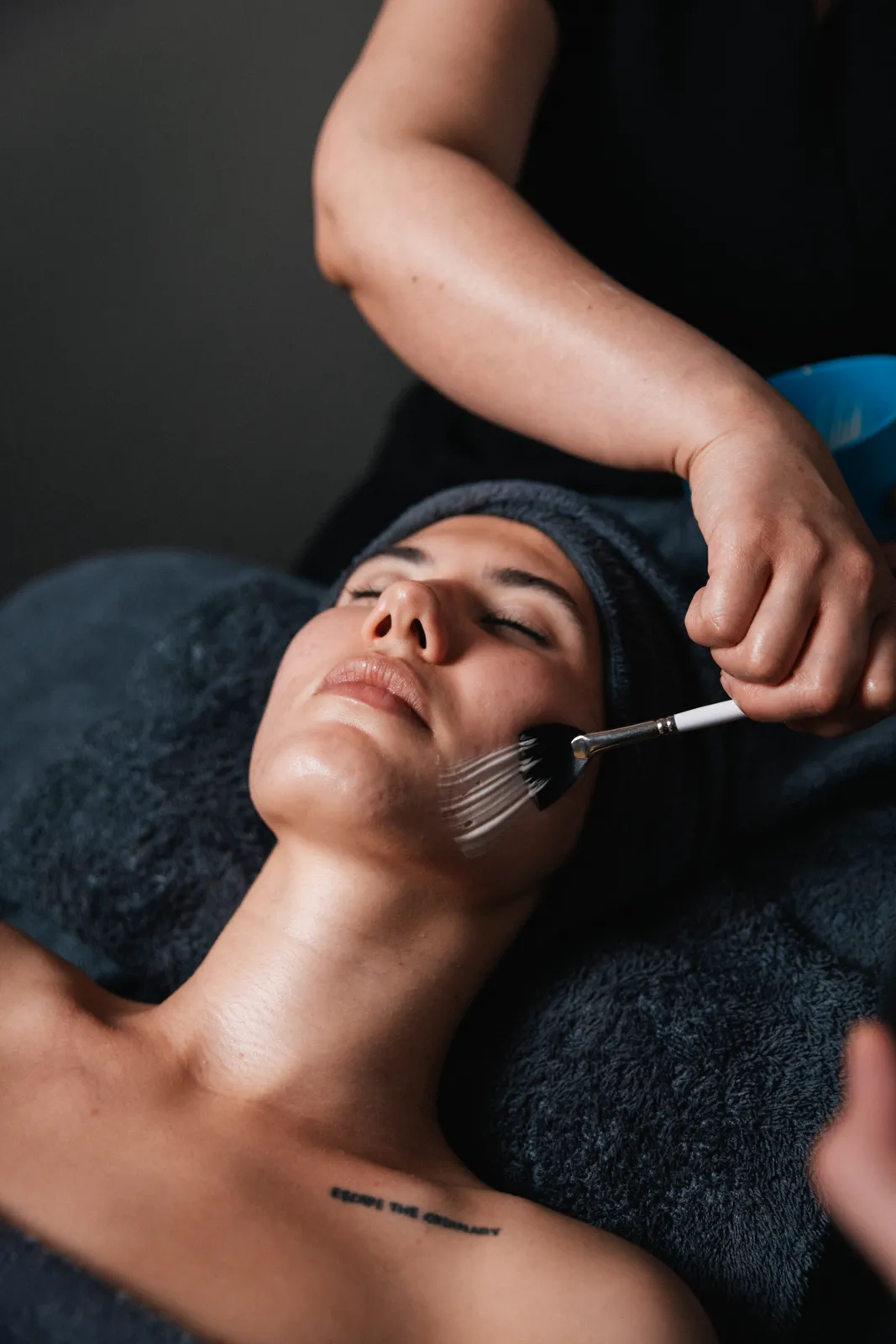 A therapist applying a facial treatment with a brush