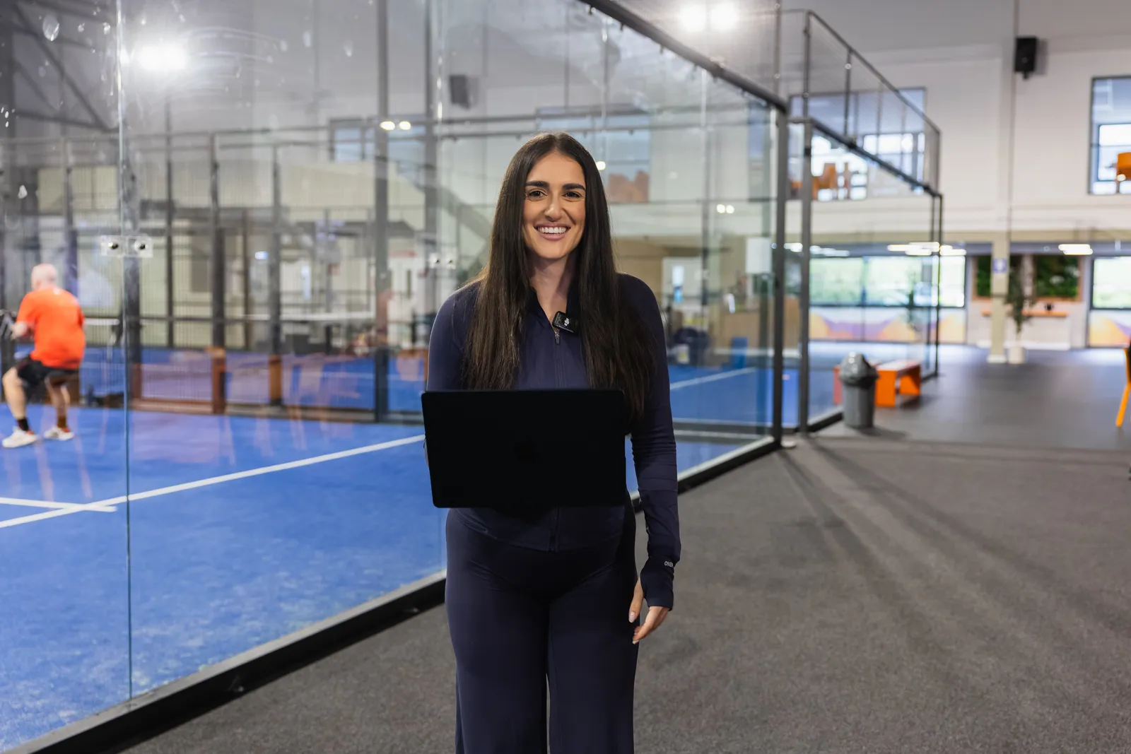 A member of the club team with a laptop beside the indoor courts