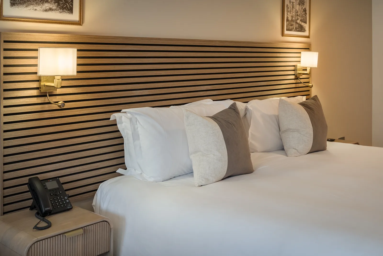 A made double bed with a slatted wooden headboard and wall lights