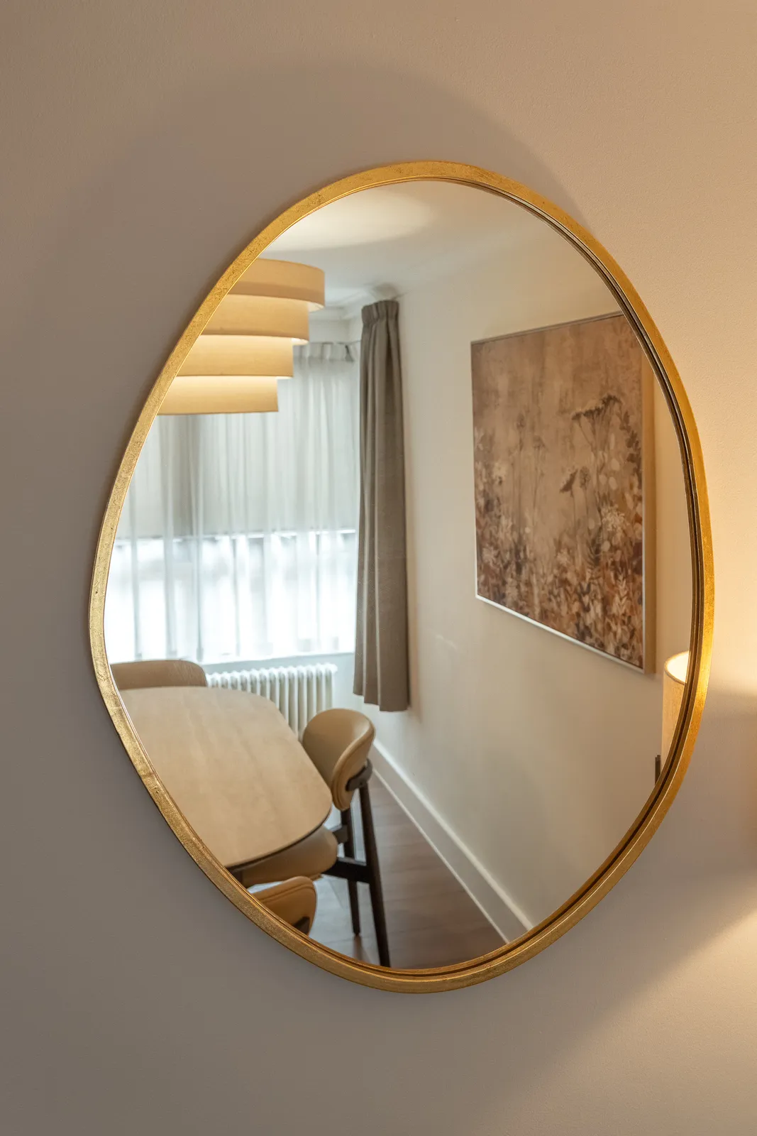 A dining table reflected in a round gold mirror
