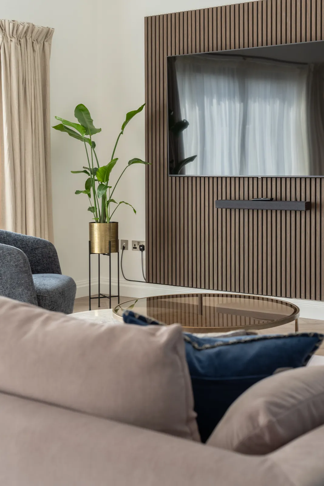 An armchair and a plant beside a slatted wooden TV wall