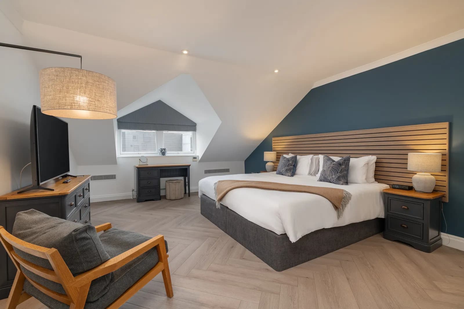 A bedroom under a sloping roof with a blue feature wall