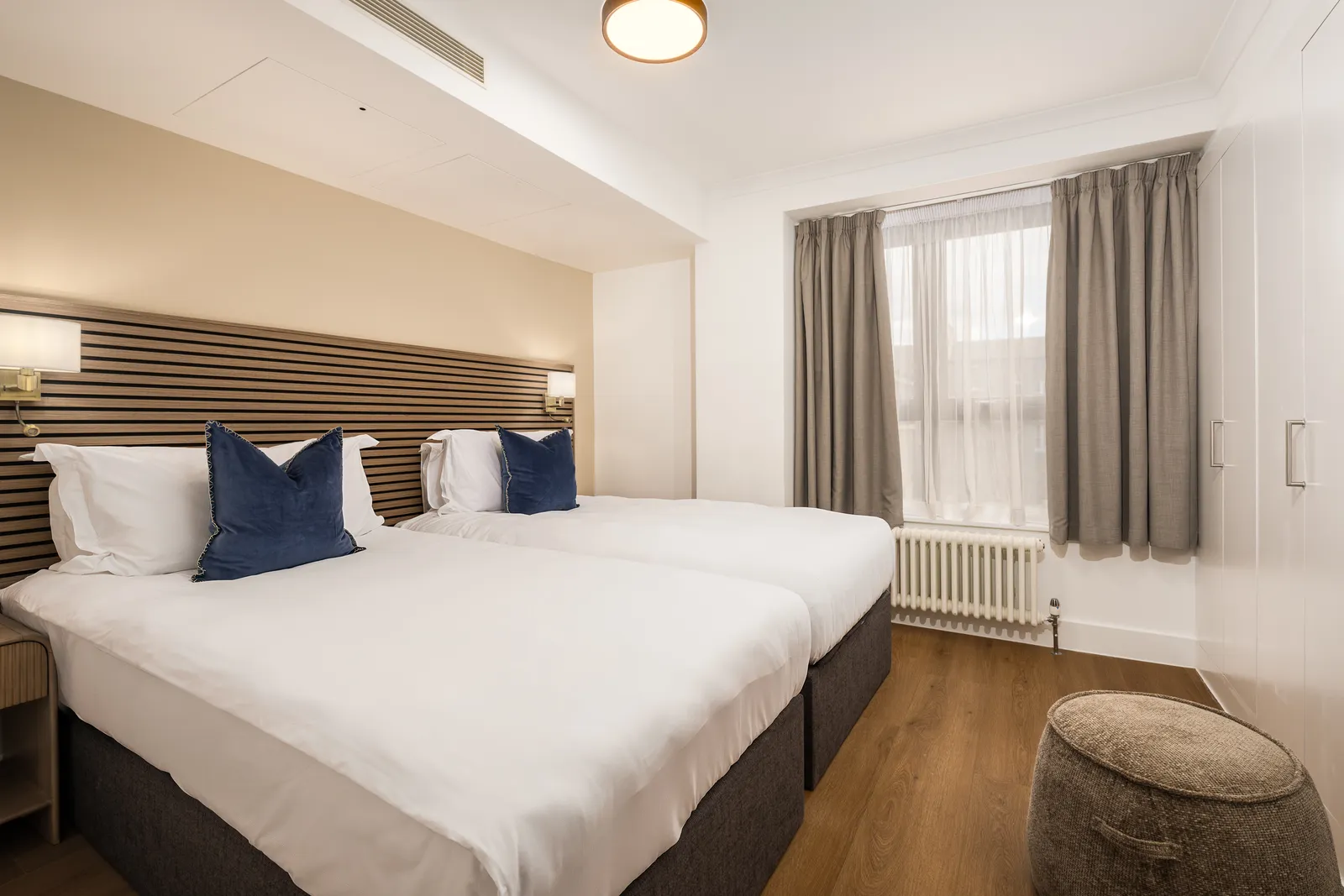 A twin bedroom with navy cushions and a large window